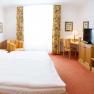 Gasthof zum Schwan, © Gerda Schmidt Ein Hotelzimmer mit Doppelbett, Schreibtisch, Fernseher und Sessel. Helle Vorhänge und florale Vorhänge schmücken das Fenster.
