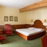 Gasthof zum Schwan, © Gasthof zum Schwan Gemütliches Hotelzimmer mit Holzmöbeln, Doppelbett, zwei roten Sesseln und einem Holztisch. Holzbalken an der Decke, grüne Teppiche und Wandbilder.