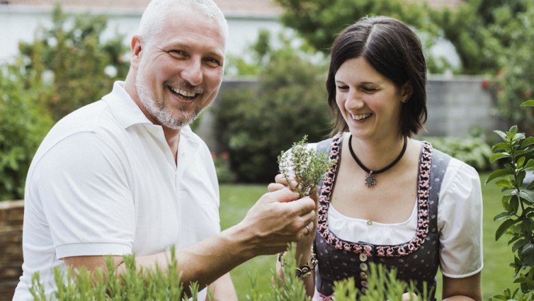 Carina und Hannes Windhör, © Niederösterreich Werbung/David Schreiber Ein Mann und eine Frau stehen lächelnd in einem Garten und betrachten Kräuter.