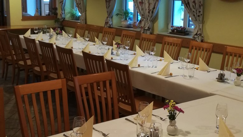 saal-familie-resch, © Familie Resch Ein festlich gedeckter Saal mit langen Tischen, Stühlen und dekorativen Vorhängen.