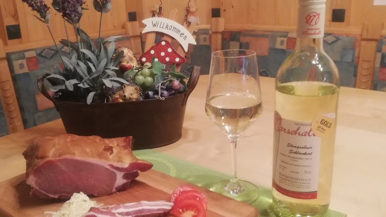 Heurigen, © Heurigenhof Marschall Ein Tisch mit Schinken, Wein und Dekoration.
