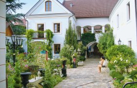Renaissancehof Kerschner, © Renaissancehof Kerschner Ein idyllischer Innenhof mit Pflanzen und einer sitzenden Person.