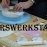Rosenhotel, © Rosencafe Person dekoriert eine Torte mit Werkzeugen und Farben auf einem Tisch.