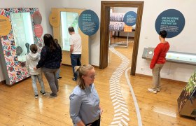 Schloss Traismauer, © WeinArtZone Menschen in einem Museum betrachten interaktive Ausstellungen mit Texttafeln und Exponaten.