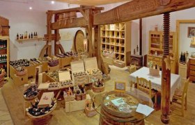 AbHofLaden, © Weingut Holzer Innenansicht eines rustikalen Hofladens mit Weinflaschen und Holzmöbeln.