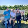 TDR-Familie Haimel, © Weingut Haimel Drei Personen stehen vor einem Weinberg neben einem Anhänger.