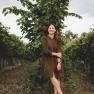 TDR-Weingut Haimel, © David Schreiber Eine Frau steht lächelnd in einem Weinberg vor einer Weinrebe.