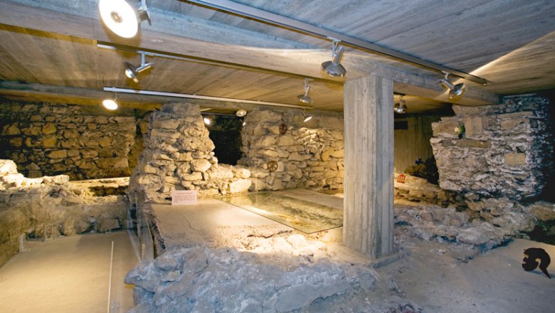 Unterkirche, © Stadtgemeinde Traismauer Unterirdische Ruinen mit Steinmauern und Betonstützen, beleuchtet durch Deckenstrahler.