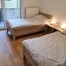 TDR-GasthofKirchenwirth-Doppelzimmer, © Josef Burger Zwei Einzelbetten in einem hellen Zimmer mit Holzboden und Balkonzugang.