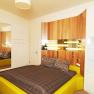 Weingut Haimel, © Fotostudio Andreas Kraus Modern eingerichtetes Schlafzimmer mit gelbem Bett und Holzverkleidung an der Wand.