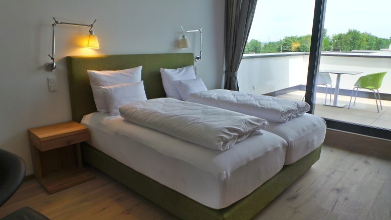 Modernes Schlafzimmer mit Doppelbett und Balkon.