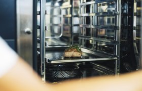 Ein Stück Fleisch mit Kräutern in einem professionellen Ofen.