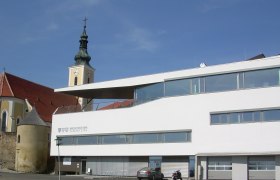 Moderne Gebäude mit Kirchturm im Hintergrund in Wölbling.