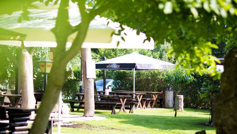 Einladender Gastgarten mit schattenspendenden Schirmen und Heurigengarnituren