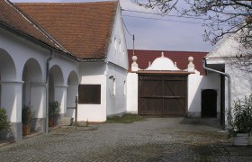 Innenhof eines Bauernmuseums mit gepflastertem Boden und weißen Gebäuden.