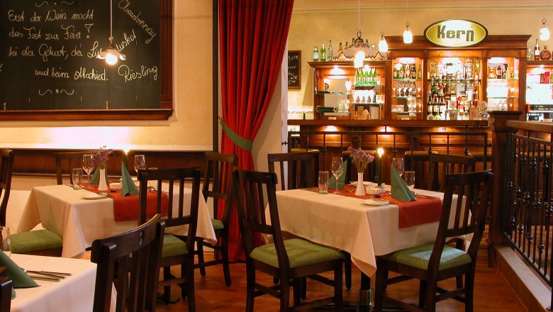 Gemütliches Restaurant mit Holzmöbeln, gedeckten Tischen und einer Bar im Hintergrund.