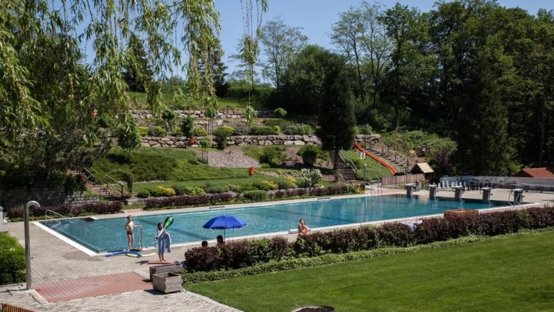 Ein Freibad mit Schwimmbecken, umgeben von Bäumen und Rasenflächen.