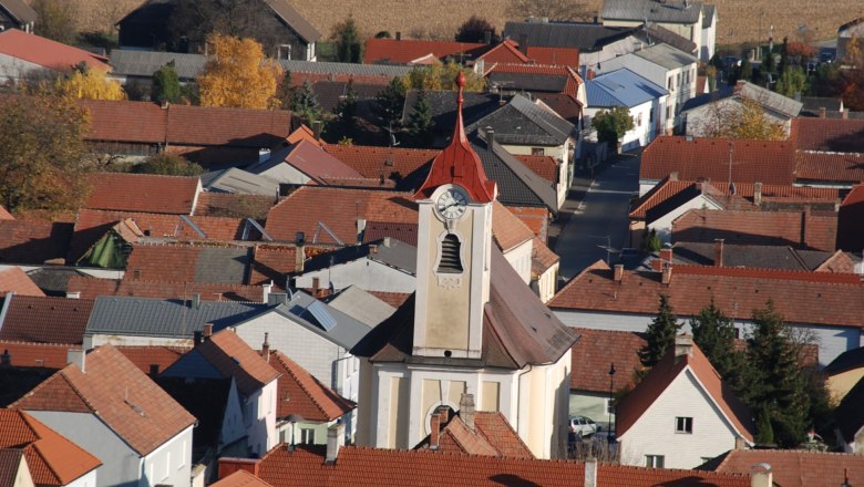 Luftaufnahme der Pfarrkirche Getzersdorf mit umliegenden H&auml;usern und Feldern im Herbst.