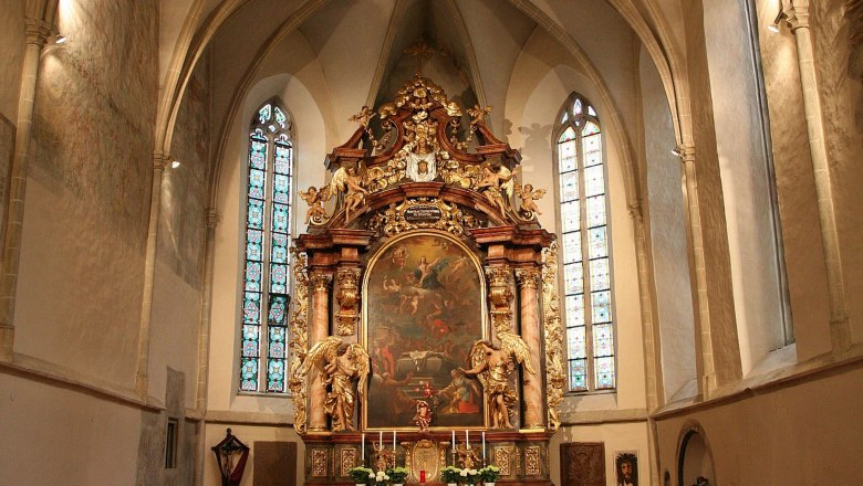Innenansicht einer Kirche mit Altar und Buntglasfenstern.