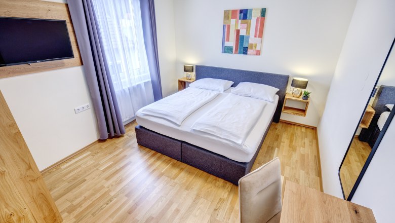Doppelzimmer mit großem Fenster und Holzfußboden