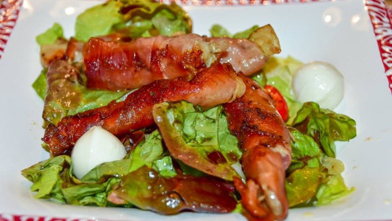 Gericht mit Karpfen im Schinkenmantel auf Blattsalat.