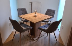 Ein moderner Esstisch mit vier grauen Stühlen in einem hellen Raum.