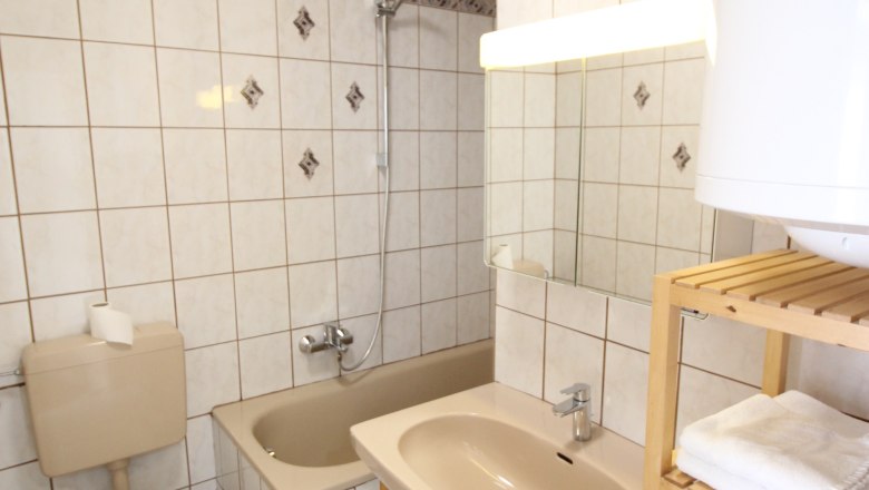 BAdezimme rmit weißen Fliesen, Badewanne und WC im Raum