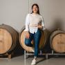 Eine Frau lehnt lächelnd an einem Weinfass im Weingut Haimel.
