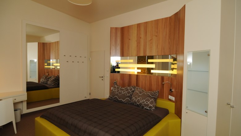 Modernes Schlafzimmer mit Holzverkleidung und gelbem Bett.