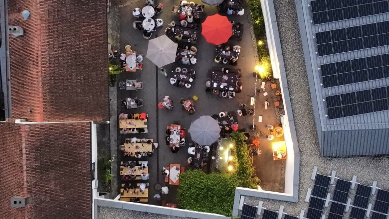 Luftaufnahme eines Weinguts mit Tischen und Sonnenschirmen im Innenhof.