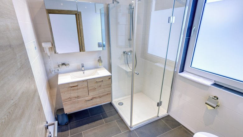 Badezimmer mit Dusche und Fenster, weiße Fliesen