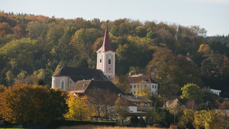 Kirche Murstetten in herbstlicher Landschaft mit B&auml;umen im Hintergrund.