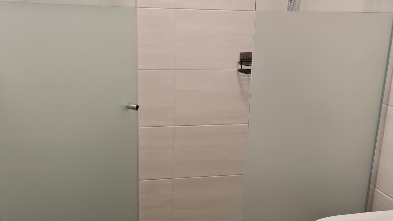 Moderne Dusche mit Glaswänden und Duschkopf in einem Badezimmer.