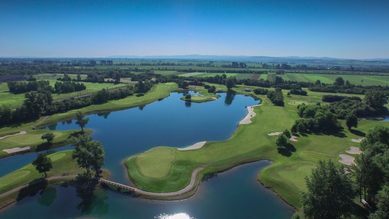Luftaufnahme eines Golfplatzes mit Wasserhindernissen und gr&uuml;nen Fairways.