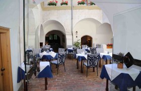 Innenhof eines Restaurants mit gedeckten Tischen und gestreiften Stühlen.