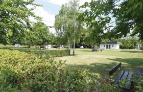 Stellplatz auf einer frisch gemähten Wiese. Om Hintergrund ein Häuschen für Sanitäranlage.