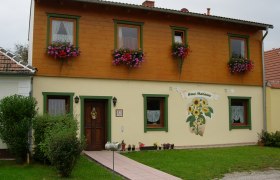 Zweistöckiges Haus mit Holzverkleidung und Blumenkästen, beschriftet als 'Haus Marianne'.