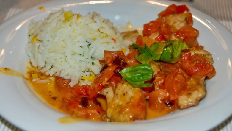 Ein Teller mit Karpfenfilet auf Tomaten-Basilikum-Ragout und Basmatireis.