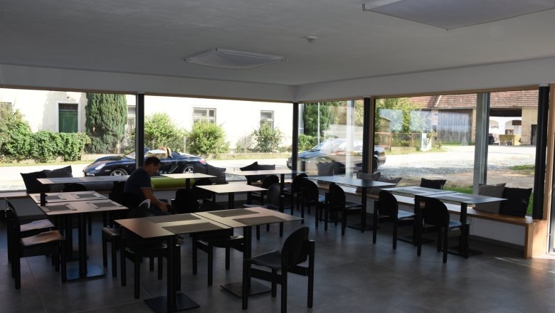 Großer Frühstücksraum mit komplett verglaster Wand und vielen Sitzmöglichkeiten.