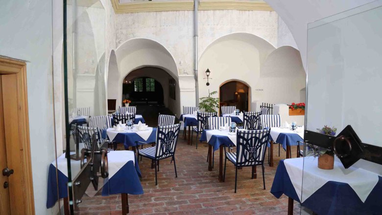 Innenhof eines Restaurants mit gedeckten Tischen und gestreiften Stühlen.