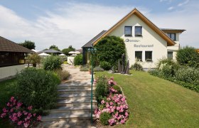 Ein Restaurant mit Garten und Terrasse, umgeben von Blumen und Büschen.