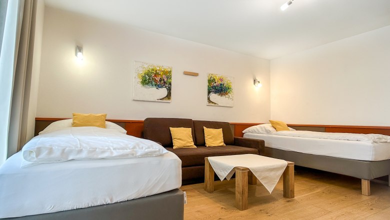 Schlafzimmer mit zwei Betten, Sofa und Tisch.