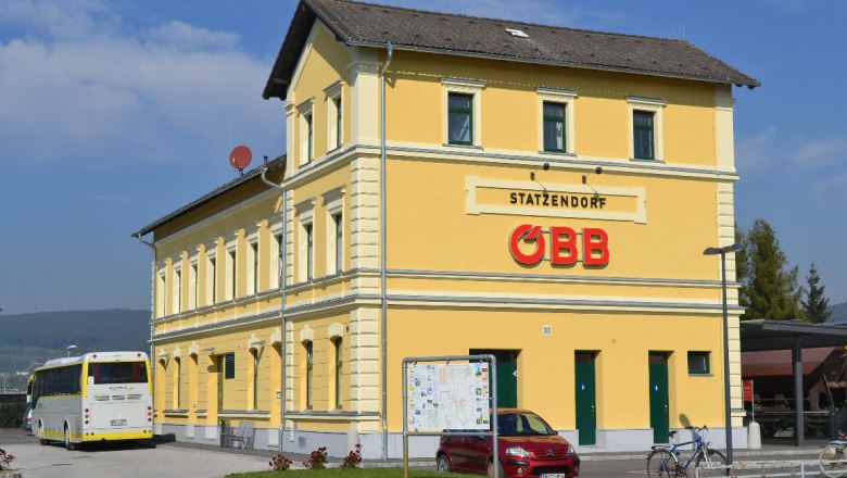 Gelbes Bahnhofsgebäude mit ÖBB-Logo und Bus im Vordergrund.