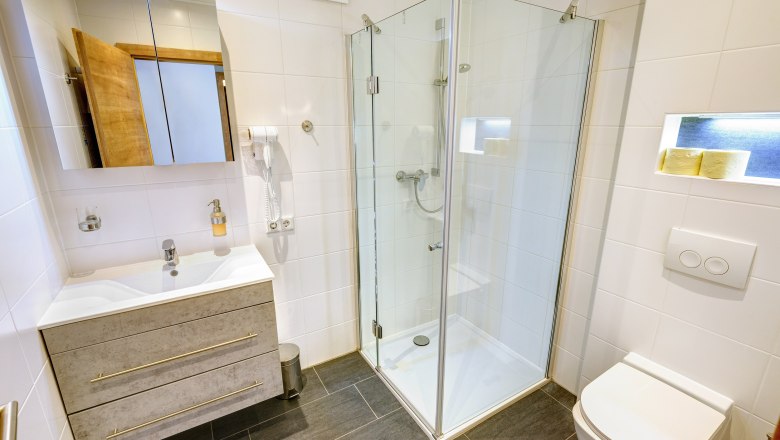 Badezimmer mit Dusche und weißen Fliesen