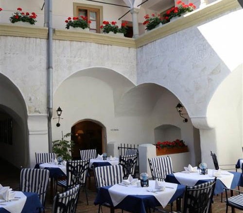 Innenhof eines Gasthofs mit gedeckten Tischen und Blumen.